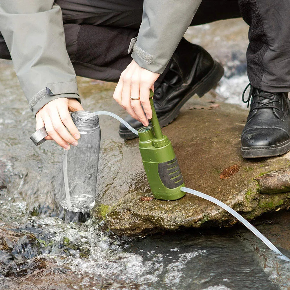 Person using a AquaVimex Portable Water Purifier pump to collect water from a stream.