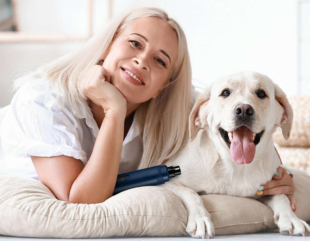 Woman lying on a couch with a white dog, both smiling.