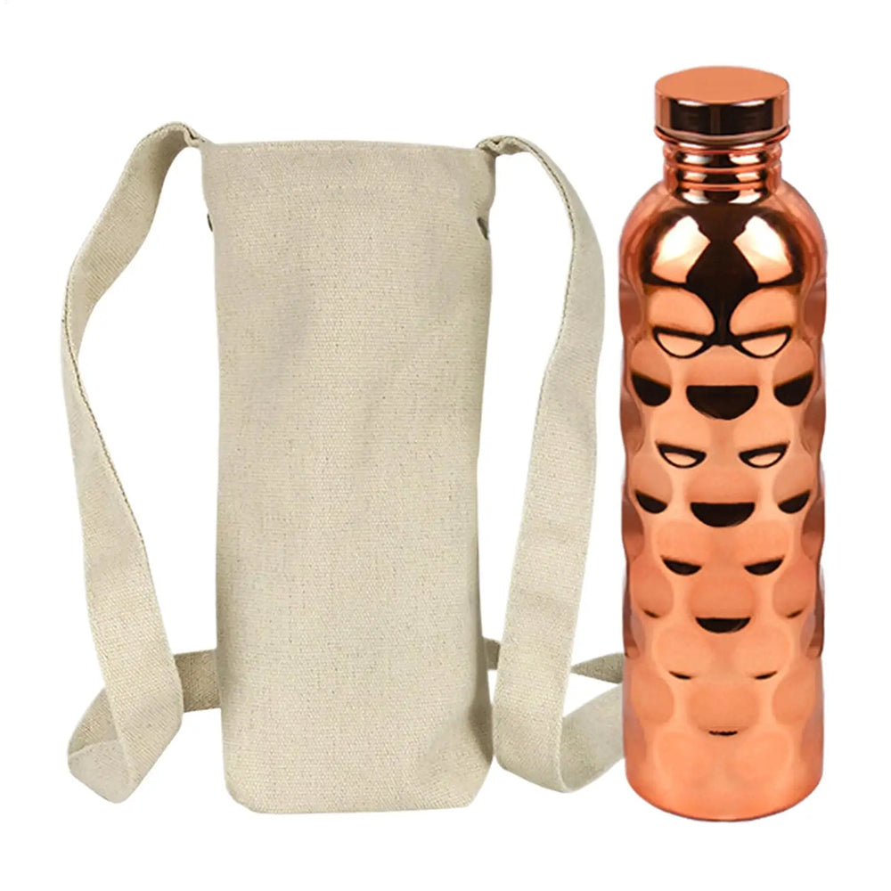 A CopperSyp Copper Water Bottle with a honeycomb pattern and a metallic cap, shown next to a beige canvas sleeve with shoulder straps on a white background.