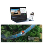 A laptop and smartphone displaying a GPS tracking and video monitoring software interface, with an aerial road-map visualization below showing a car's real-time location and speed on a forest road.