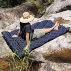 Person lying on a blue sleeping pad in a natural outdoor setting