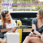 Two women sitting in the bed of a truck, one playing an acoustic guitar and the other holding a handheld microphone. A white portable FolbGent Karaoke Machine is in the foreground, with a yellow hard case behind them.
