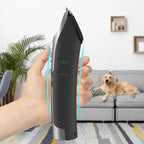 Hand holding a black and silver FuriCutx Dog Hair Clipper with a dog on a couch in the background