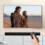 Person holding a remote control in front of a TV displaying two people in futuristic outfits.