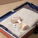 Krevont Steamer with cable on a folded blanket inside an open suitcase.