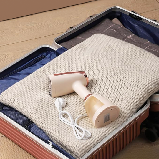 Krevont Steamer with cable on a folded blanket inside an open suitcase.
