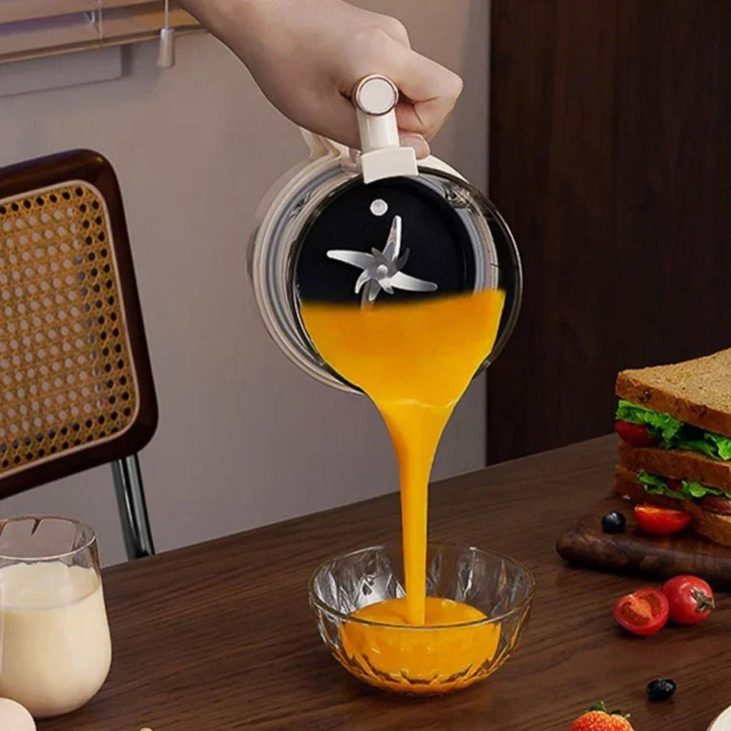 Person pouring orange liquid from a container with a blade into a glass NutyClax Nut Milk Maker on a table.