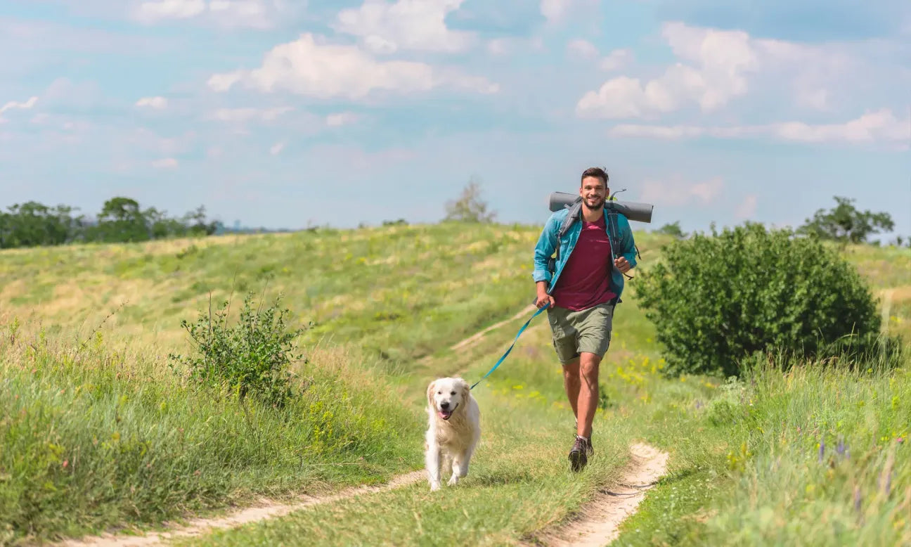 Man running with a dog on a trail in a grassy field