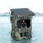 A waterproof PawnixCam Solar Wildlife Camera with a built-in solar panel on top, shown partially submerged in splashing water.