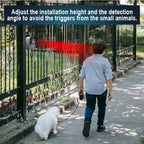 Person walking a dog with a SeniWav Driveway Sensor camera mounted on a fence, indicating the need to adjust installation height and detection angle.