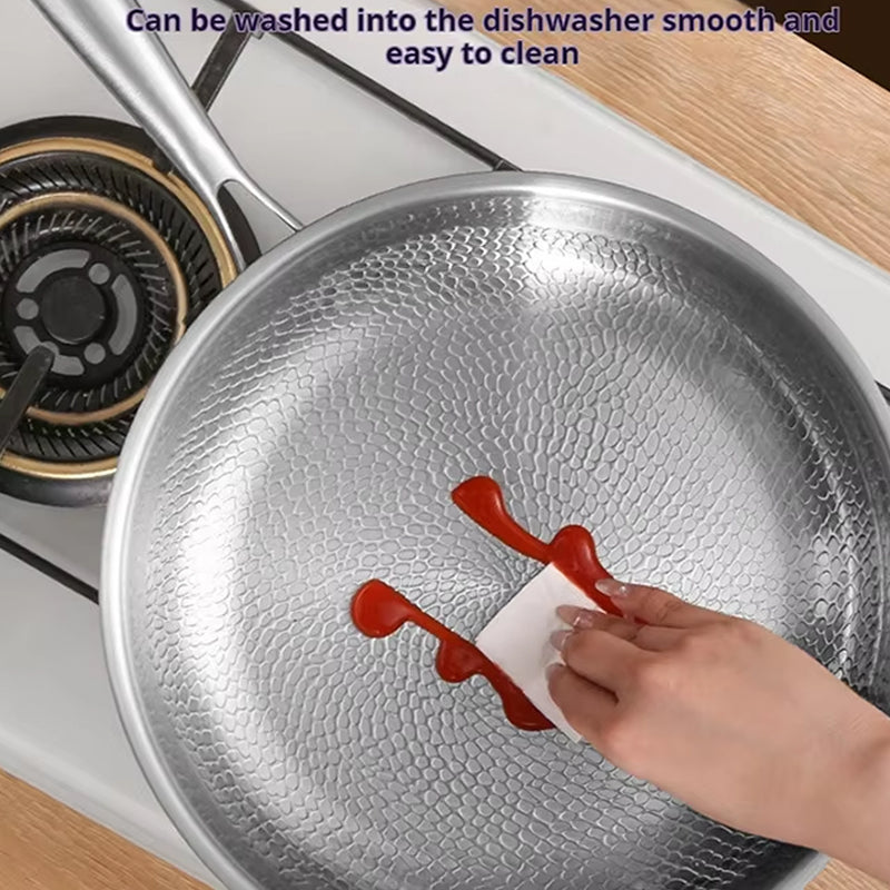 TikaxPan Titanium Frying Pan with a hand using a paper towel to wipe up ketchup, placed on a stove.