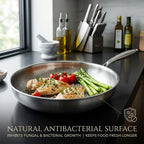 Tossenium Titanium Frying Pan with food on a kitchen counter, featuring a natural antibacterial surface.