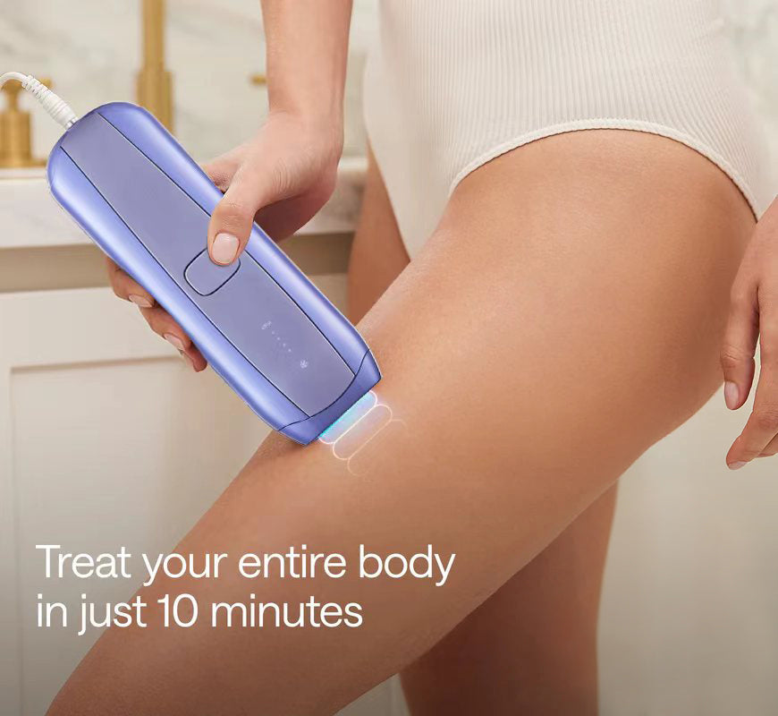 Person using a purple Veliss Pro 10S IPL Hair Removal Device on their leg with text 'Treat your entire body in just 10 minutes' in a kitchen setting.