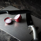 Sliced red onion on a Wavel Titanium Cutting Board with two knives.